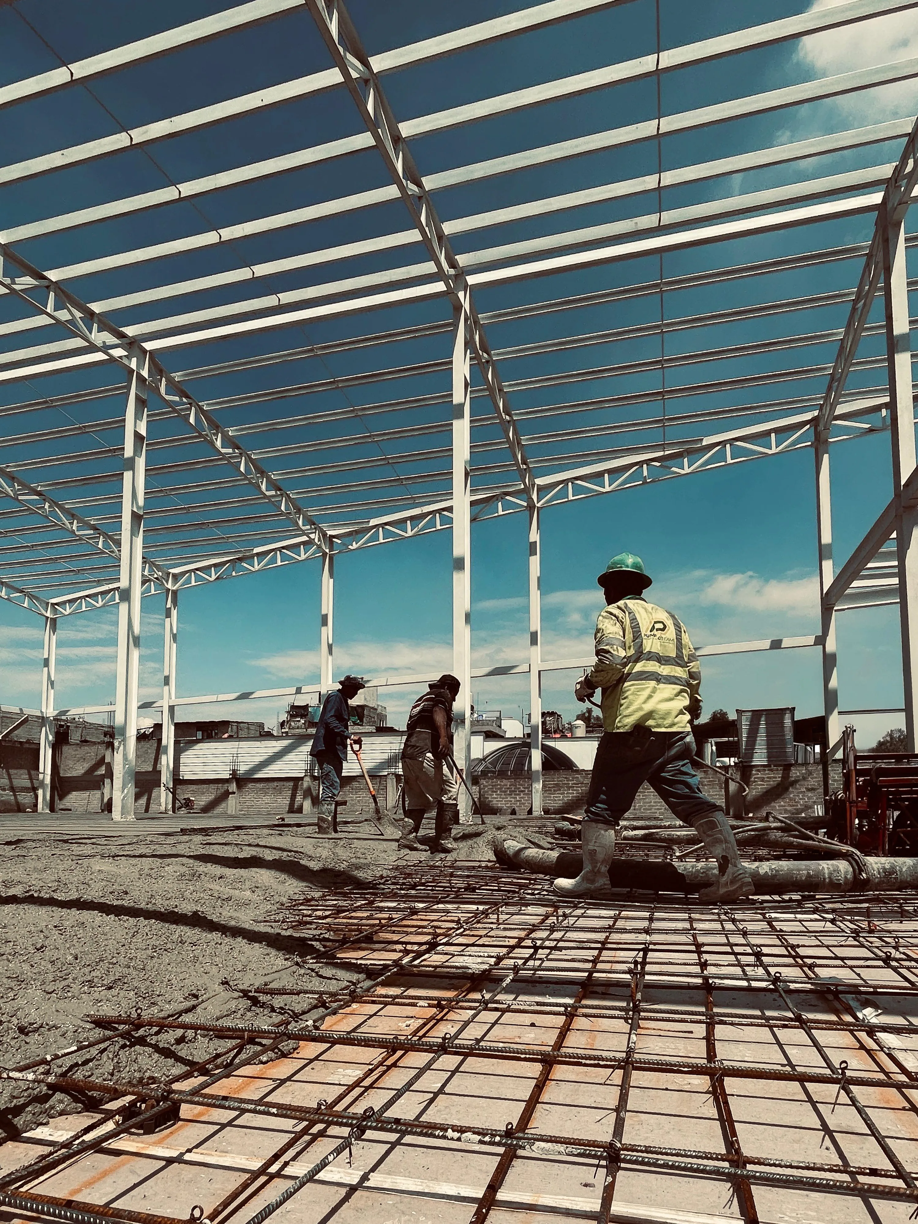 Cuadrilla trabajando sobre armado de acero en obra de nave industrial.