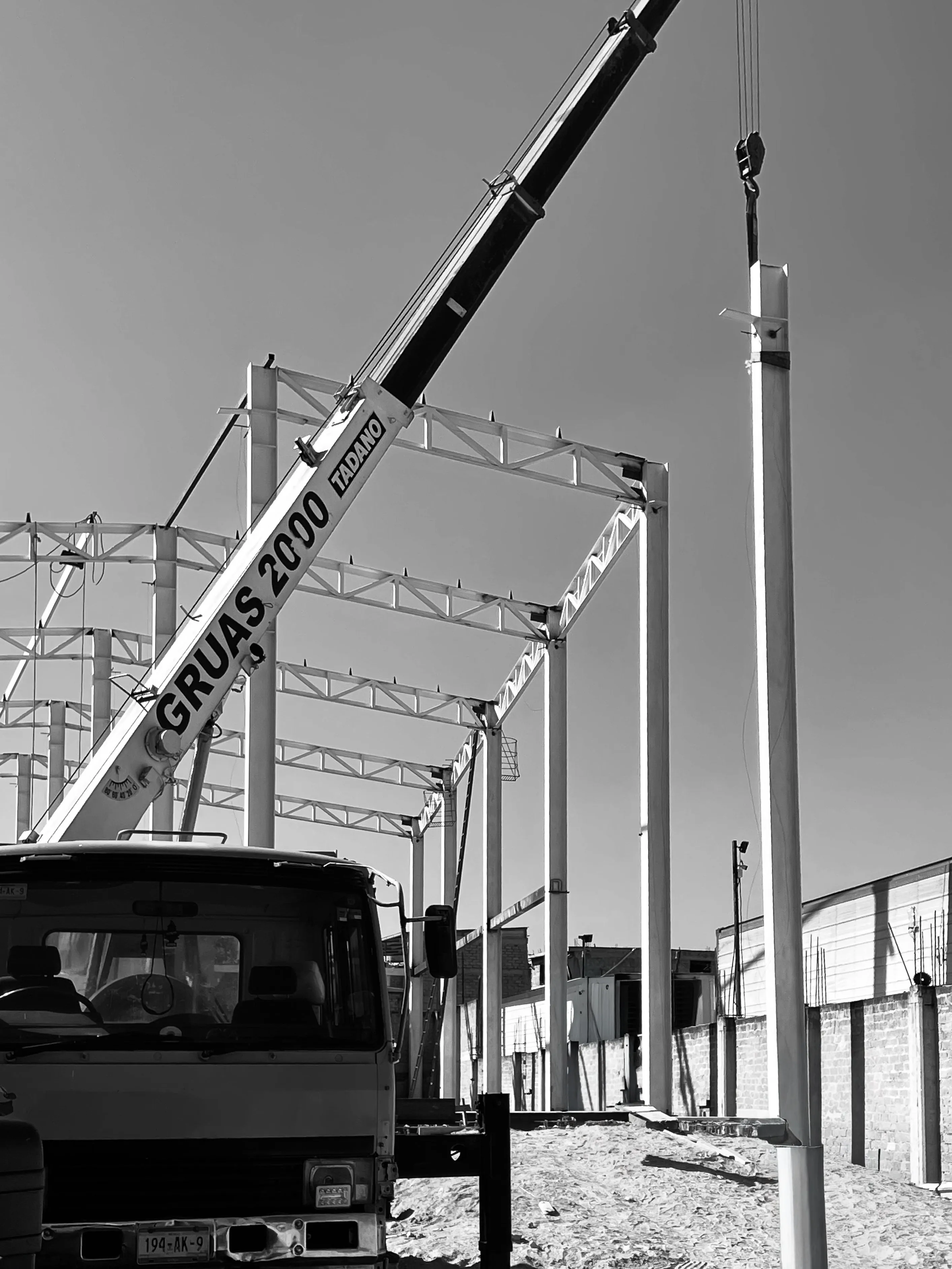Grúa industrial Tadano colocando elementos estructurales durante construcción de nave.