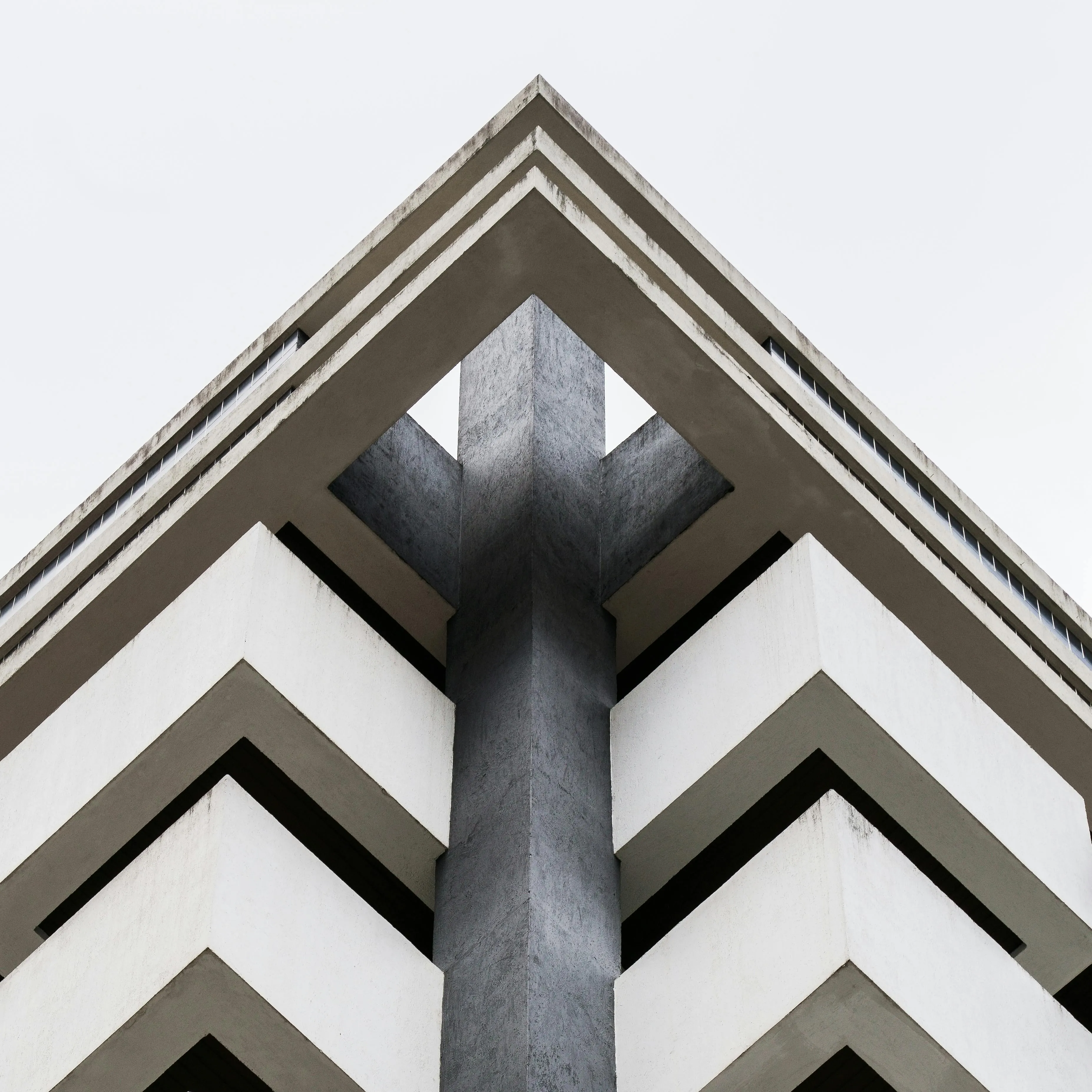 Edificio de concreto y volúmenes blancos visto desde abajo en contrapicado.