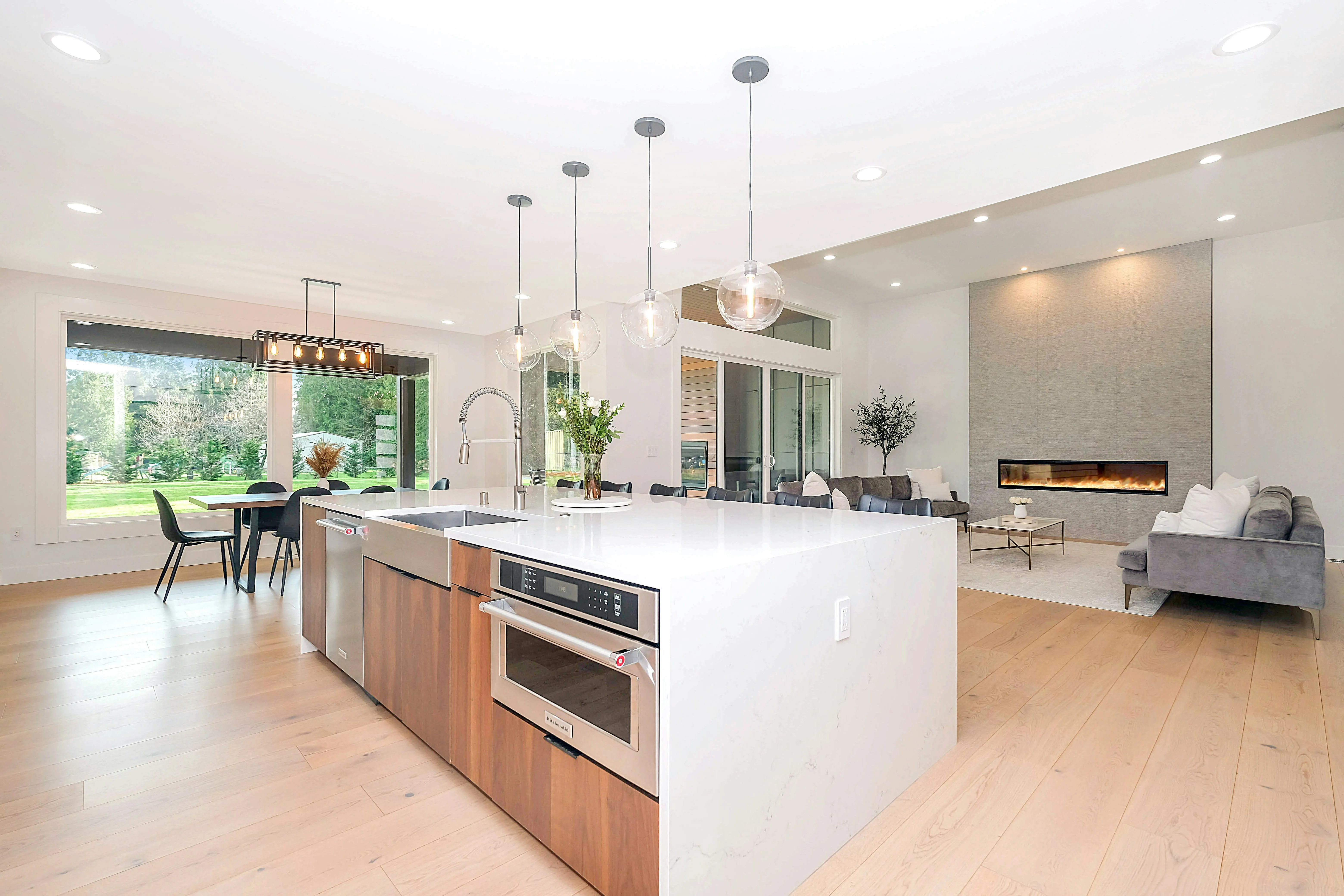 Cocina remodelada con barra de mármol, sala con chimenea y comedor con lámparas colgantes.